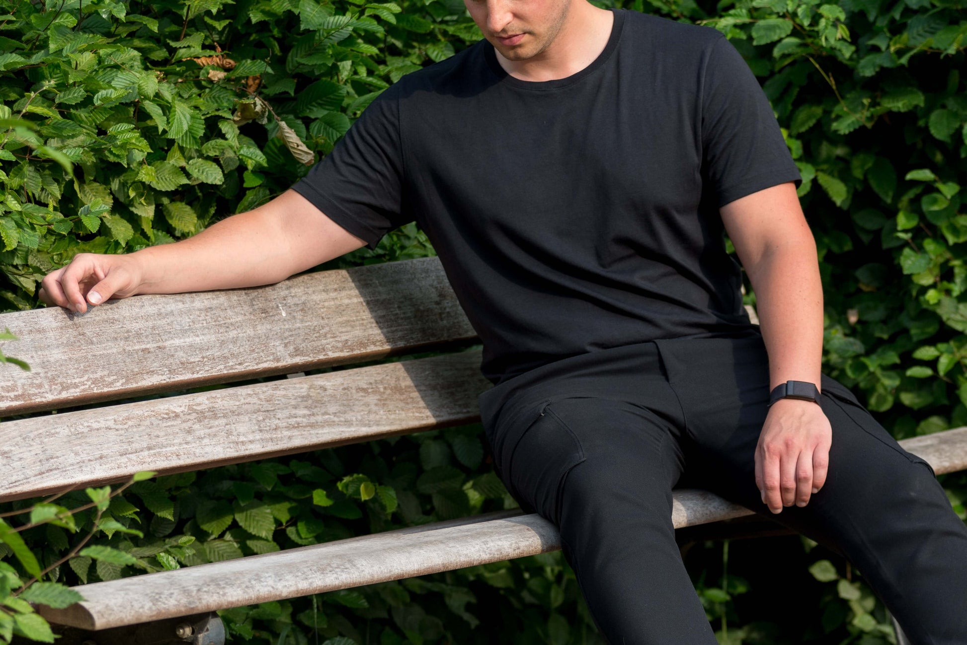 mann sitzt mit schwarzem lyocell shirt auf einer parkbank