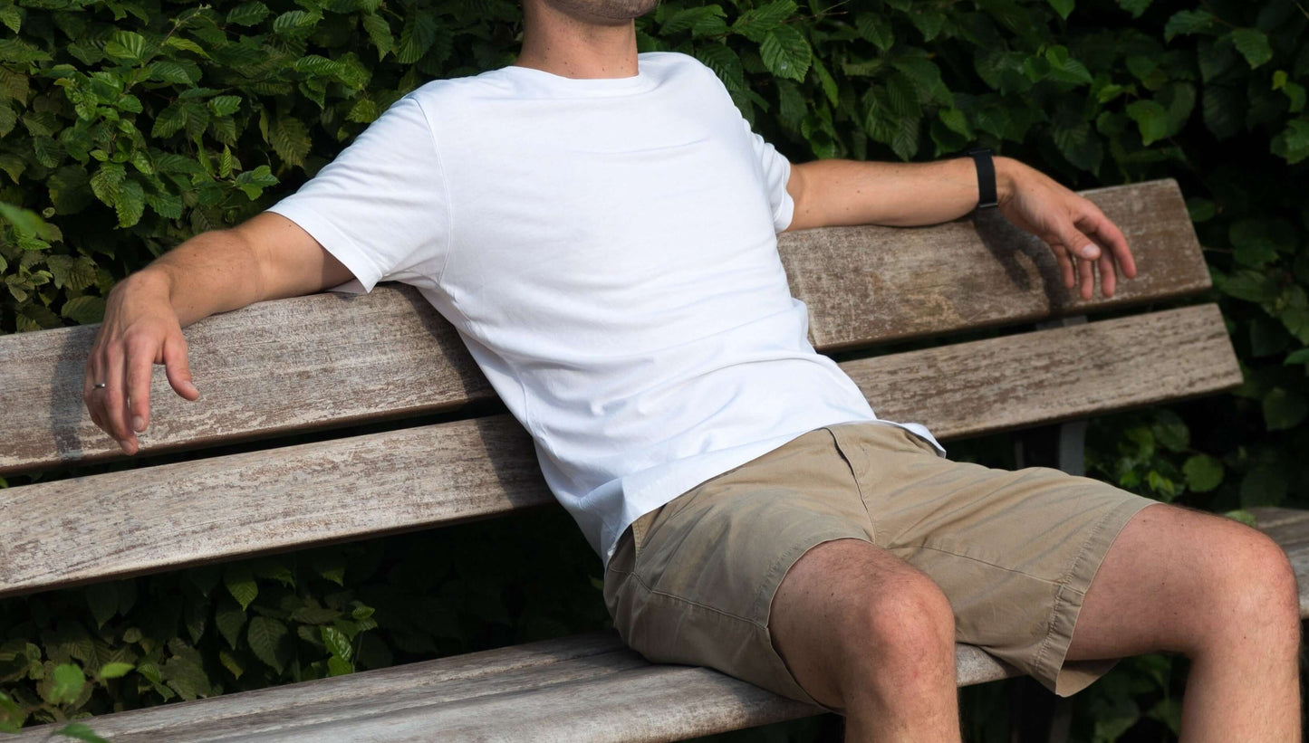 mann sitzt mit weißem lyocell shirt auf einer parkbank