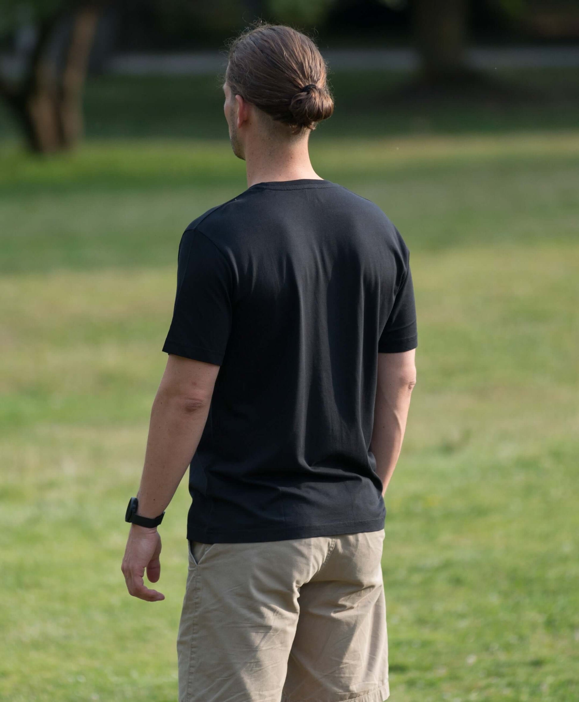 mann steht mit schwarzem lyocell shirt auf einer wiese