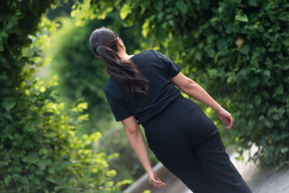 frau mit schwarzem lyocell shirt geht durch einen durchgang im park