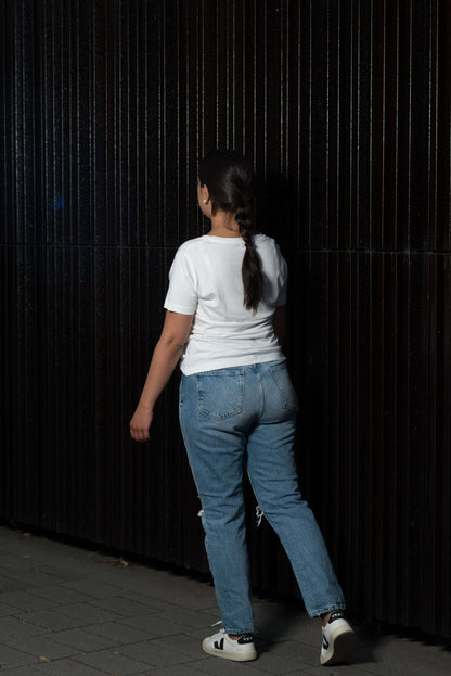 gehende frau mit weißem lyocell shirt vor einer wand